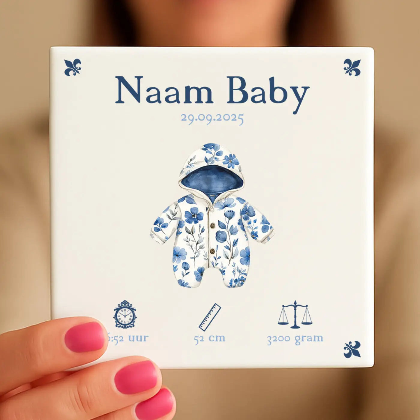 Witte keramische baby tegeltje met blauw rompertje en navy blauwe fleur de lis motieven voor geboorteaankondiging