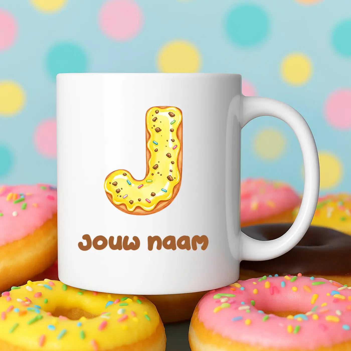 Witte keramische mok met een cartoonillustratie van een gele donutf met chocoladechips en regenboogsprinkles vormgegeven als de letter j