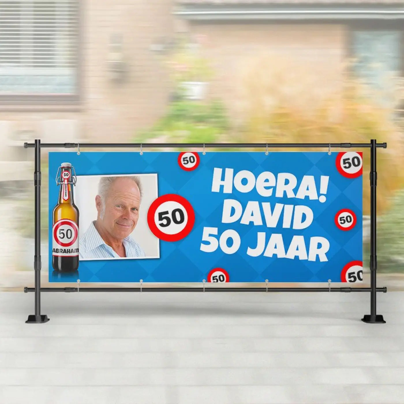 Blauwe spandoek abraham met witte tekst hoera david 50 jaar, rode verkeersborden, foto van man en bierflesillustratie